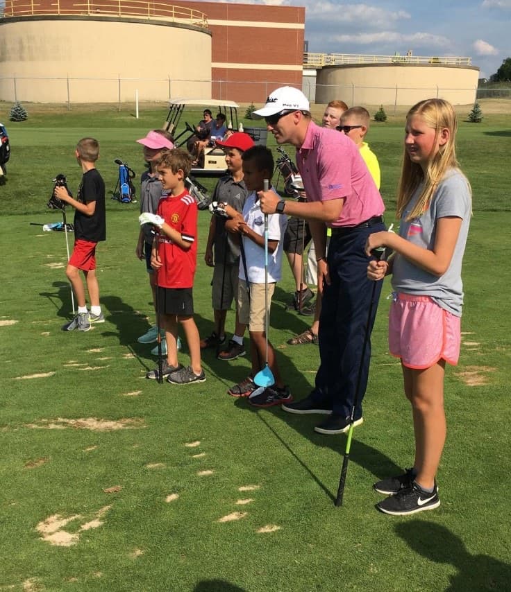 Kyle Martin leading a junior clinic on the range at The Fortress, young golfers lined up with clubs