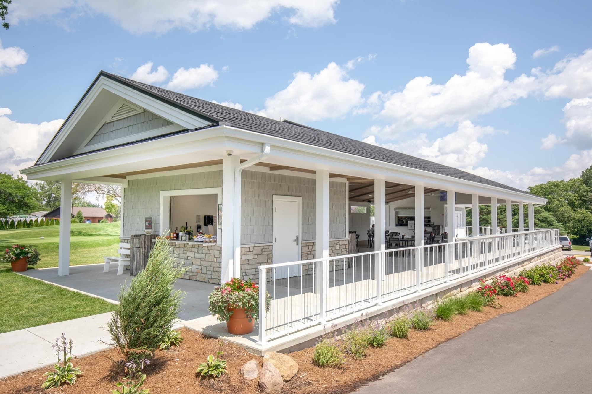 Exterior of the Fortress Pavilion in summer, covered porch with white railings and the bar under the roofline